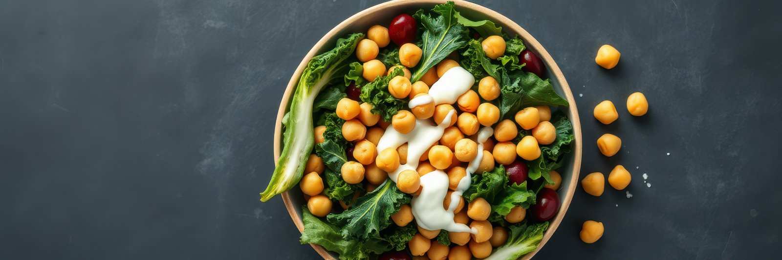 Colorful salad with chickpeas, greens, and creamy dressing served in a wooden bowl